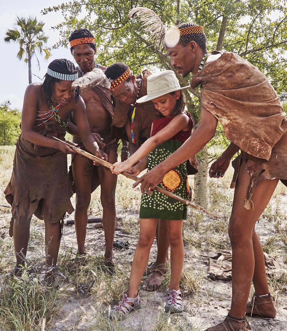 san bushmen at jacks camp botswana showing child how to use a bow